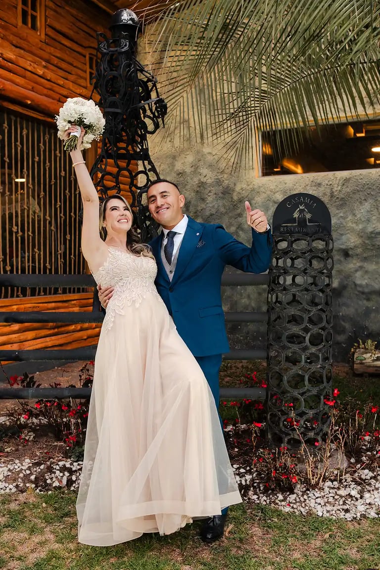 Recién casados celebrando sonriendo a cámara. La novia levanta el ramo y disfrutan de su momento juntos en Quito, Ecuador