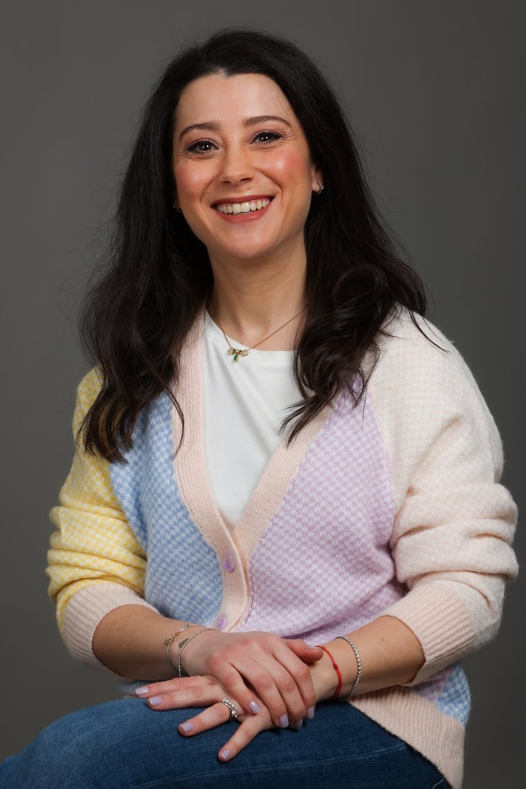 a woman in a colorful sweater and jeans sitting on a chair