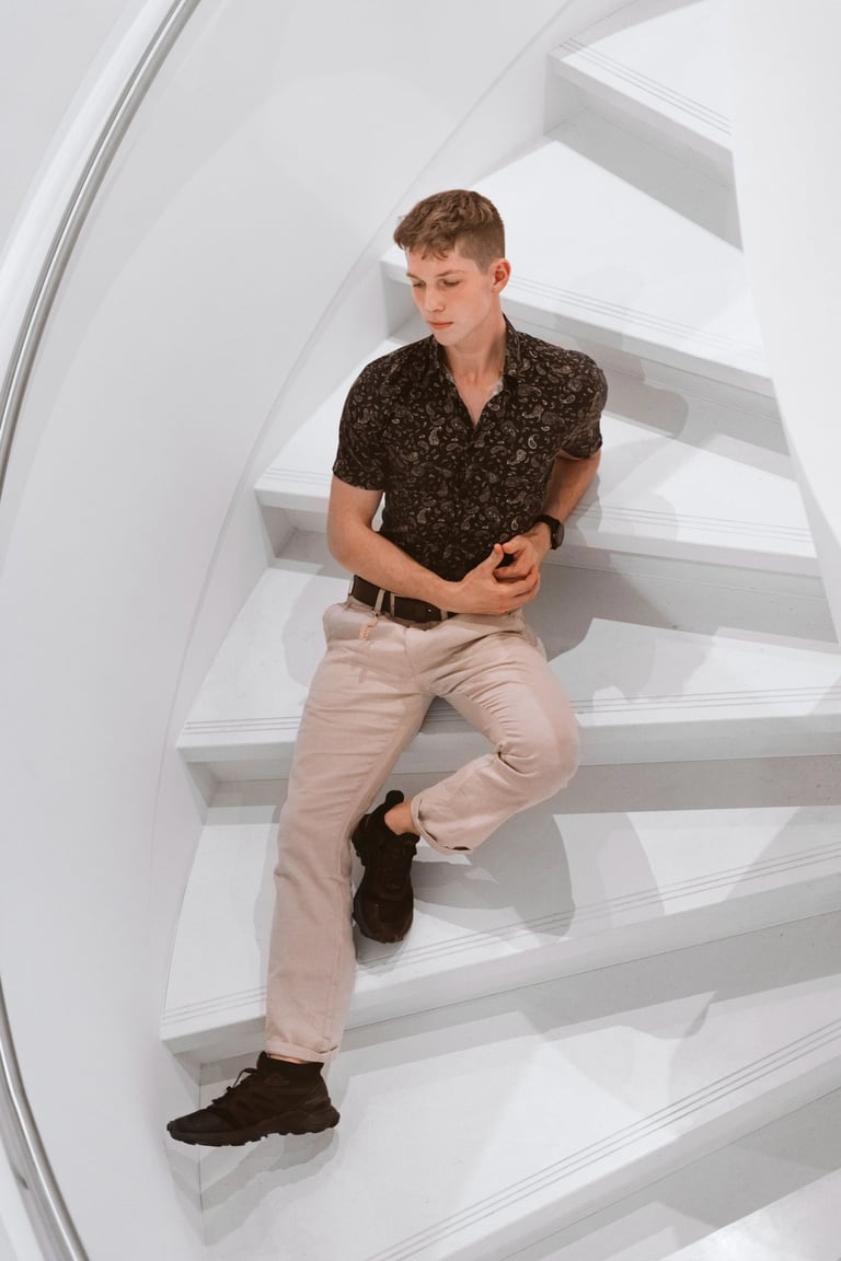 Portrait photo of a young man sitting on white stairs
