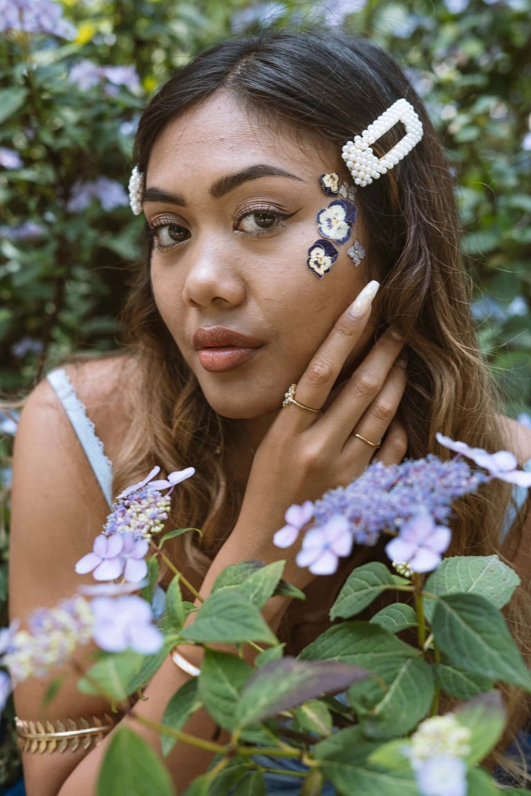 Portrait photo of a young Indonesian woman in a park with flowers and whimsical blue dress