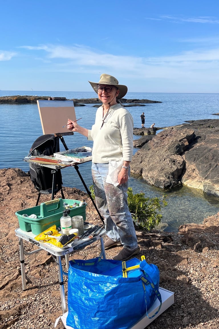 A photo of Margaret Moss, painting at Presque Isle Park in Maquette, Michigan.