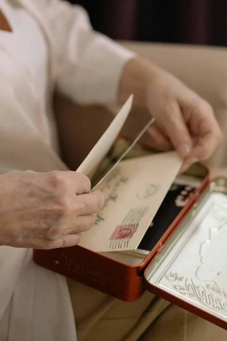 Hands opening a vintage metal tin filled with old letters and stamped envelopes.