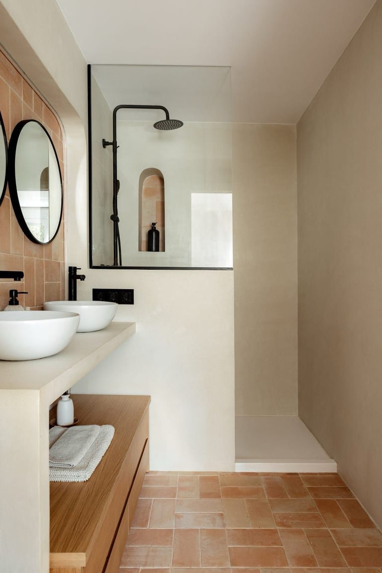 Modern bathroom with microcement walls, double sinks, terracotta tile flooring, and glass shower enc