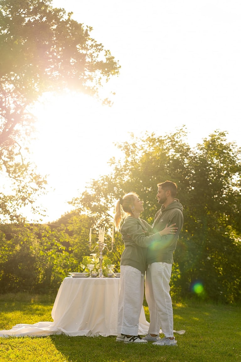 A couple embracing during a romantic outdoor dinner at sunset in a garden.