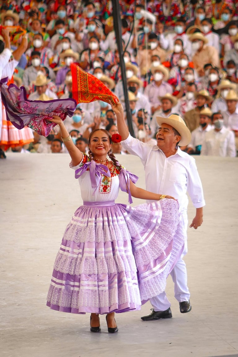 Pareja bailando danza folclórica mexicana en la Guelaguetza, Oaxaca, con trajes regionales