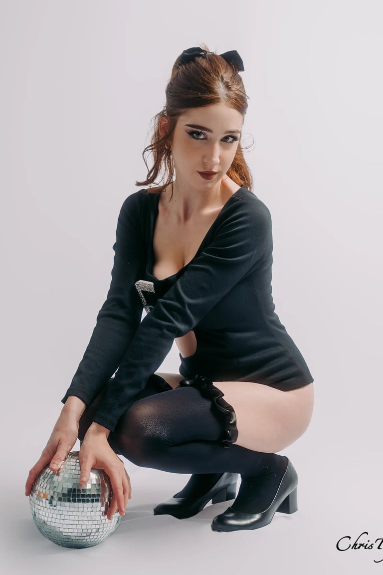 Shooting Perpignan jeune femme en body noir et bas sombres, accroupie avec une mini boule à facettes