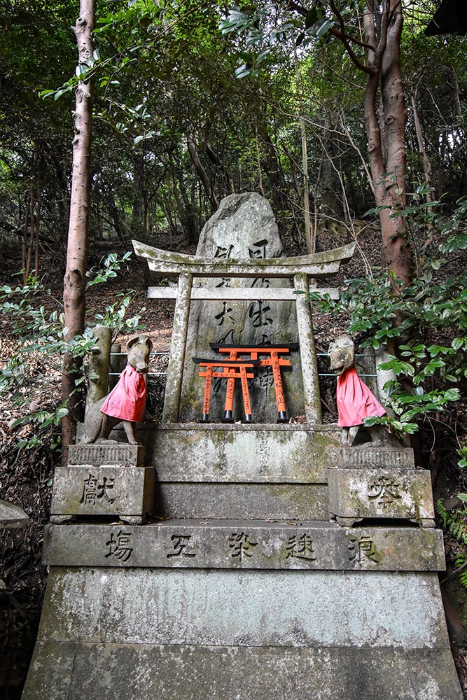 Petit sanctuaire dans la montagne avec des mini portes torii et deux kami renards sur les cotés