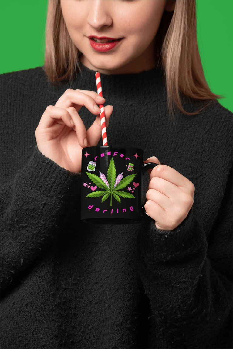 a woman holding a straw and drinking from a mug with cannabis imagery