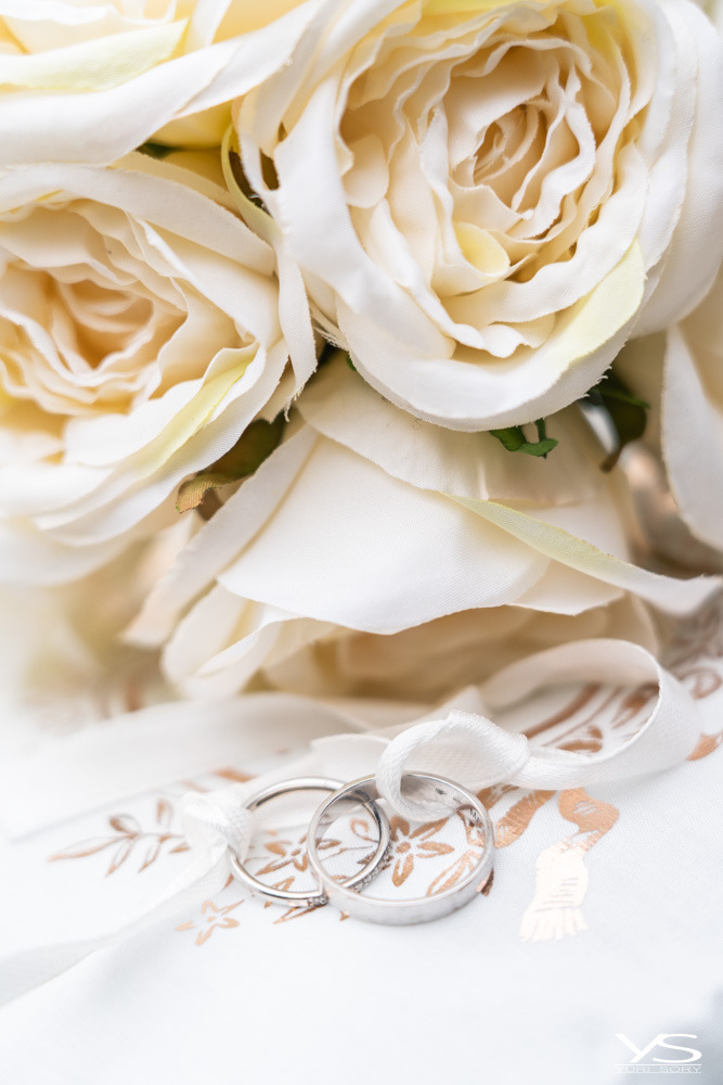 a bouquet of white roses and wedding rings