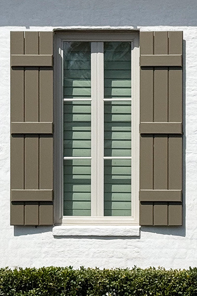 exterior board and batten shutters in brown on white brick