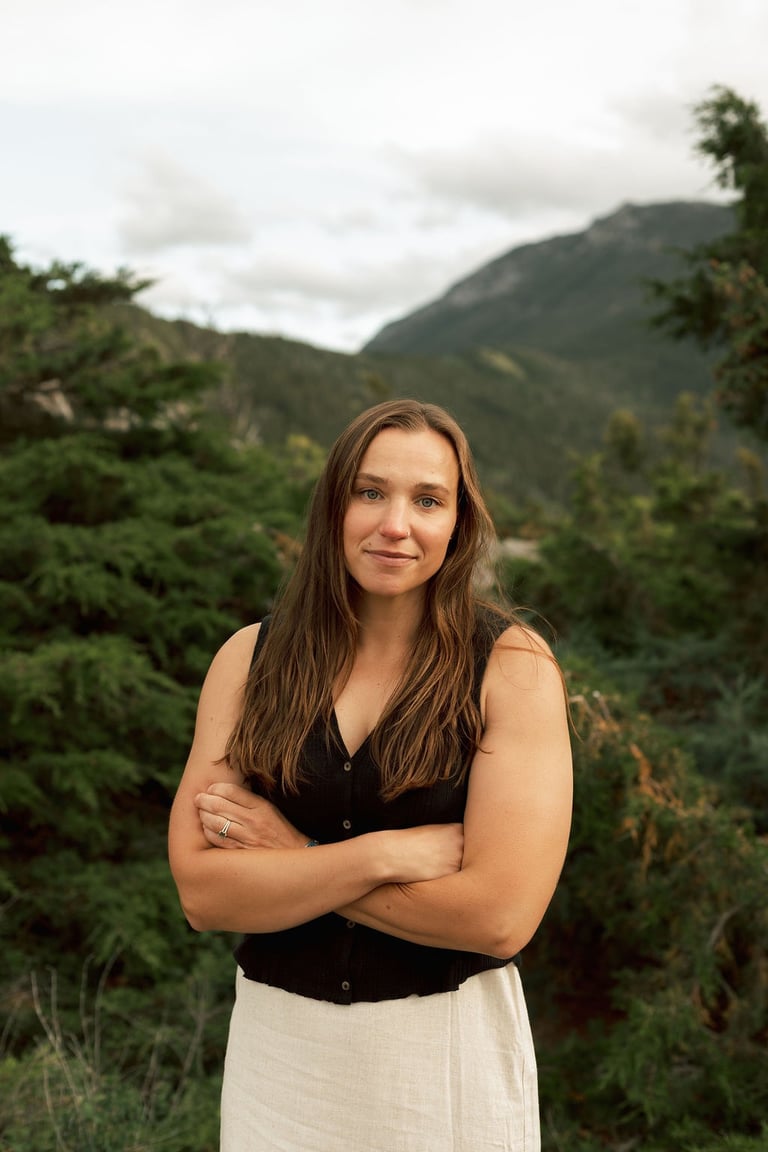a woman in a white dress standing in front of a mountain