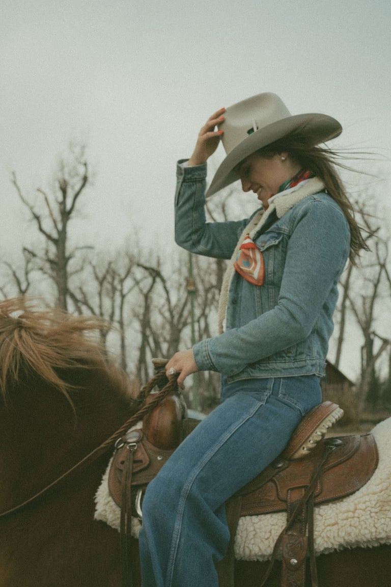 a woman in a cowboy hat sitting on a horse