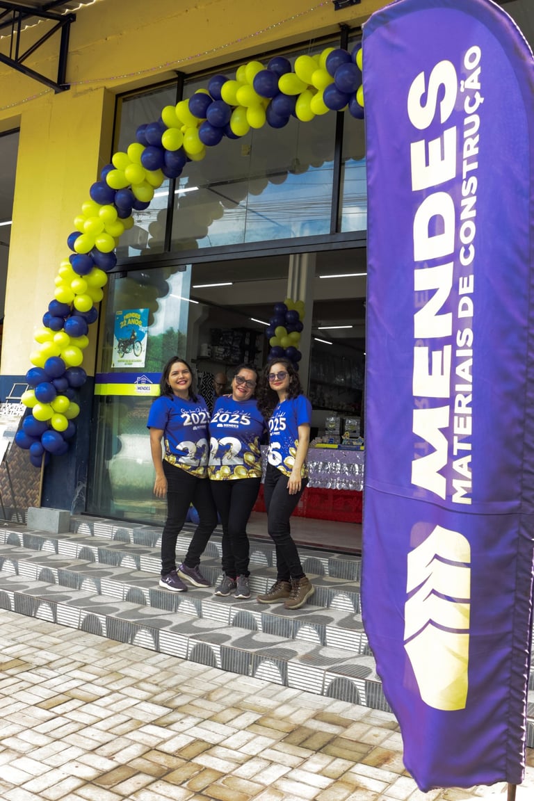 foto de colaboradores, em segundo plano, na frente da loja, bandeira com logo, em primeiro plano.