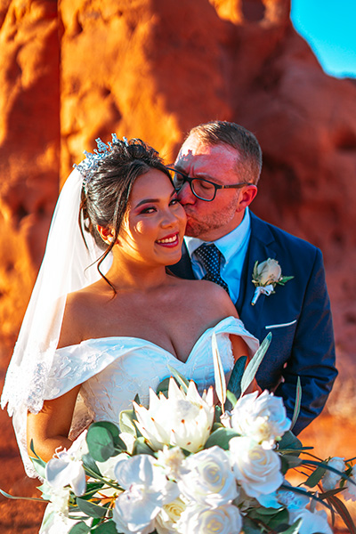 a man and woman in wedding attire standing in front of a mountain