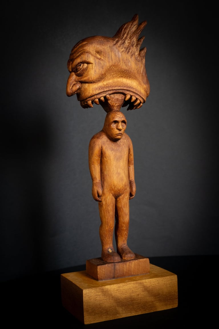 Hand-carved wood sculpture depicting a surreal creature head biting a human figure.