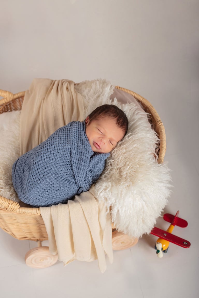 un bebé recién nacido dormido en un cesto de paja con un avión de juguete