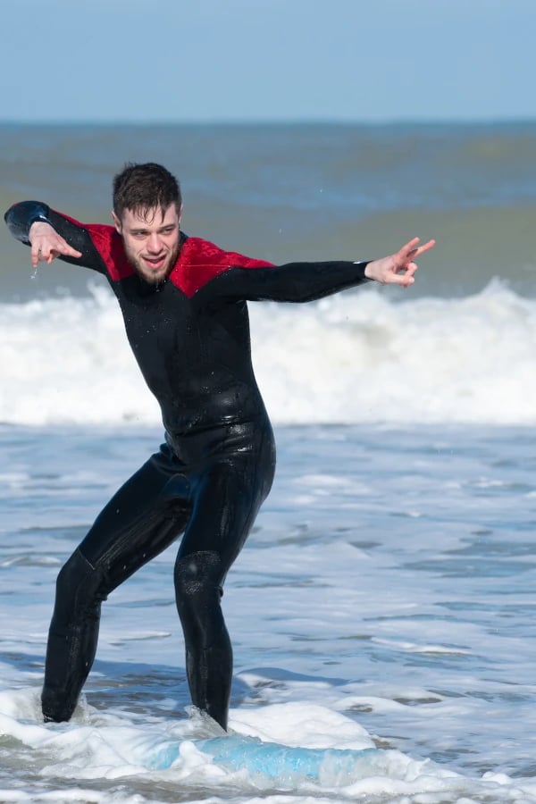 Une homme en combinaison en train de poser sur une planche de surf dans l'océan