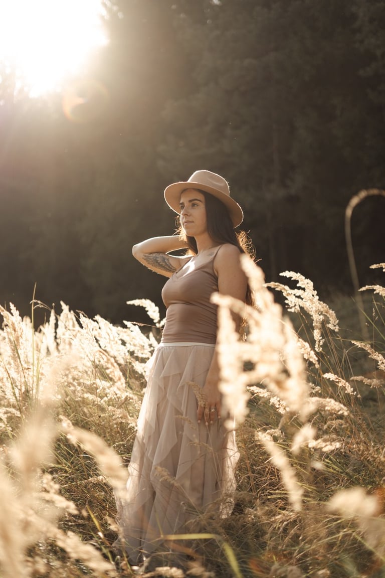 woman standing in long grass during sunset
