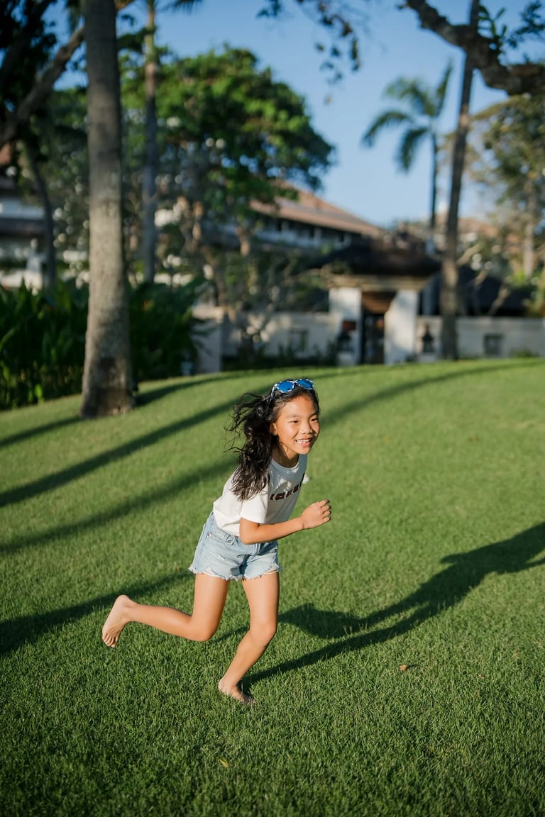 Young girl running across the lawn during a family photography session at InterContinental Bali Resort