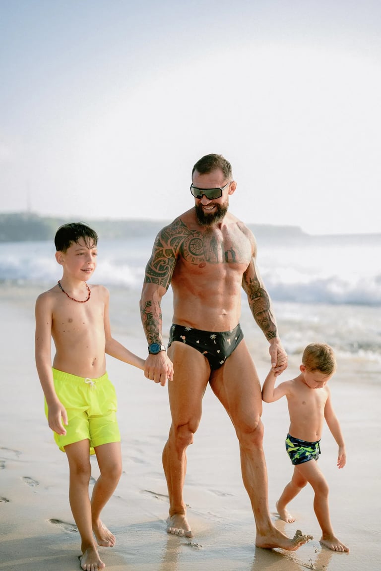 Father walking along the shoreline with his children during a relaxed family photography session at Dreamland Beach Bali.