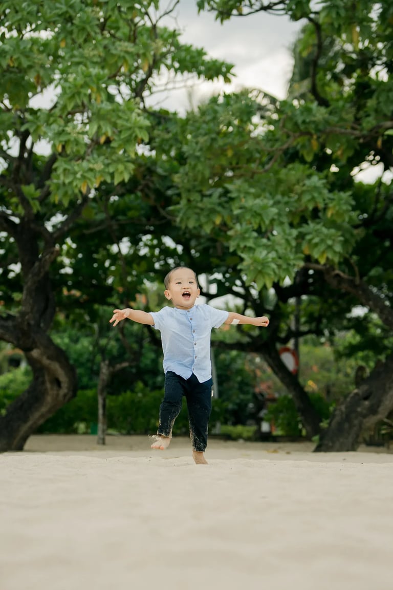 Young boy running joyfully along the beach during a family session at Nusa Dua Beach Bali