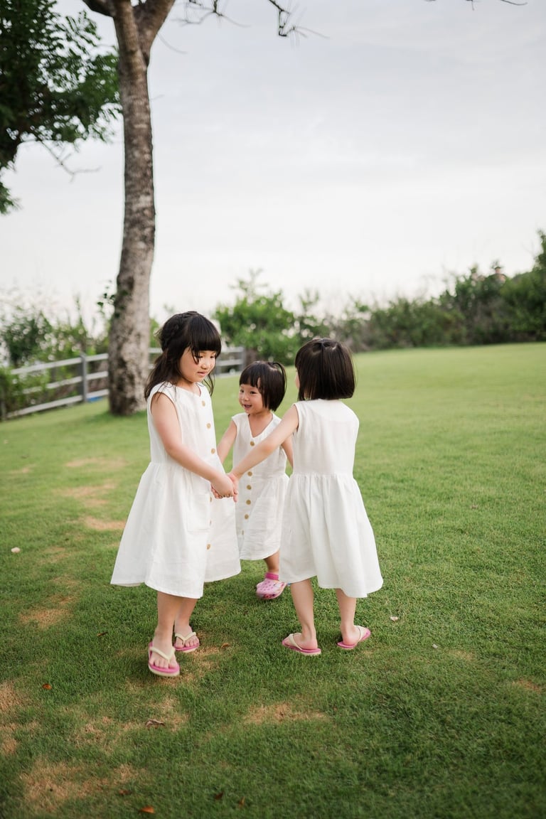 Two sisters playing together on the grass during a family photography session at The Mulia Nusa Dua Bali