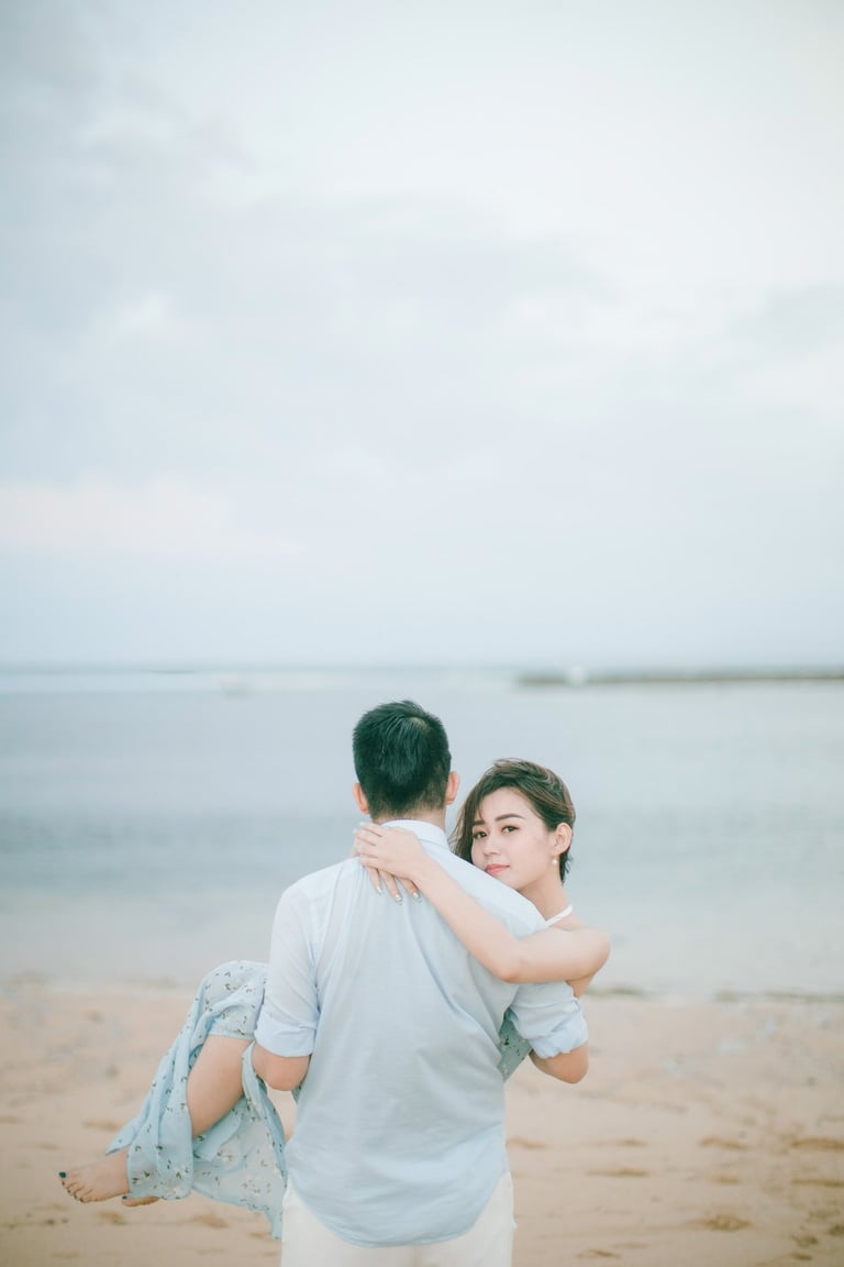 Romantic couple embracing by the ocean at Sofitel Bali Nusa Dua Beach Resort.