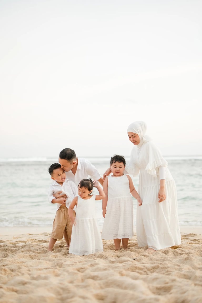 Warm and intimate family portrait of Ilham family at Melasti Beach Bali during golden hour