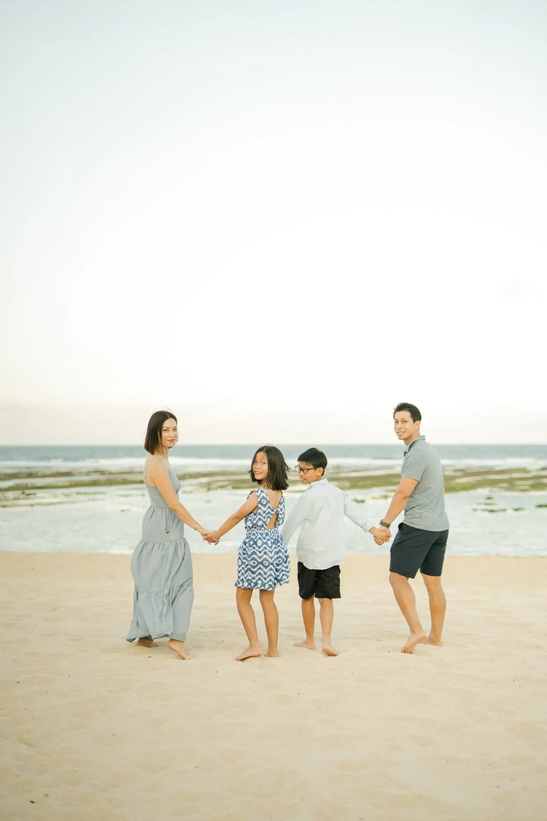 Family walking together along the shoreline during a luxury family photography session at The Ritz-Carlton Bali.