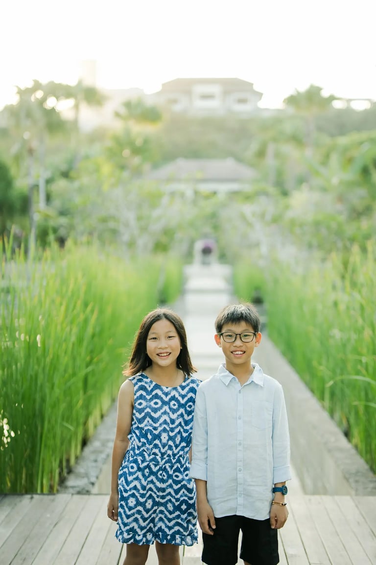 Brother and sister standing on a garden boardwalk during a luxury family photography session at The Ritz-Carlton Bali.