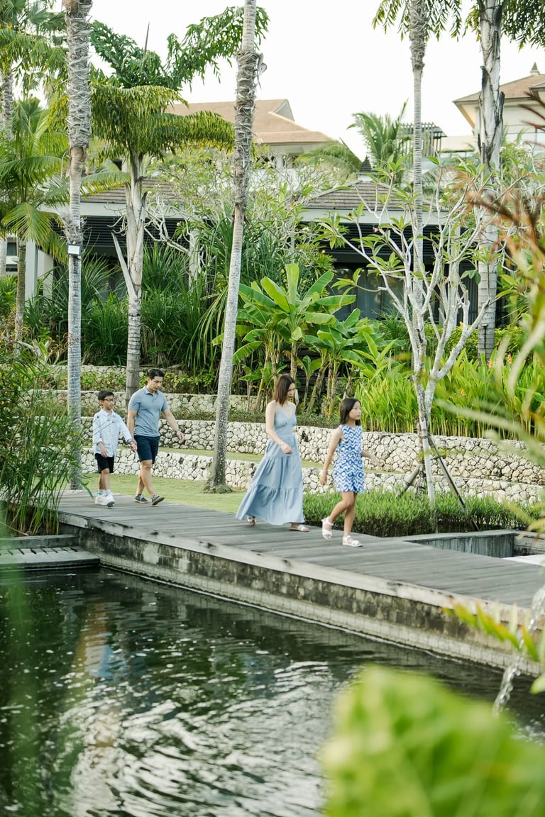 Family walking beside a reflecting pond during a luxury family photography session at The Ritz-Carlton Bali.