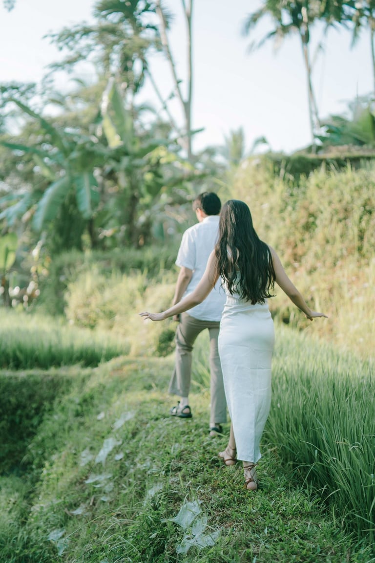 Intimate couple walking along the rice terrace path at sunrise in Tegalalang Ubud Bali.