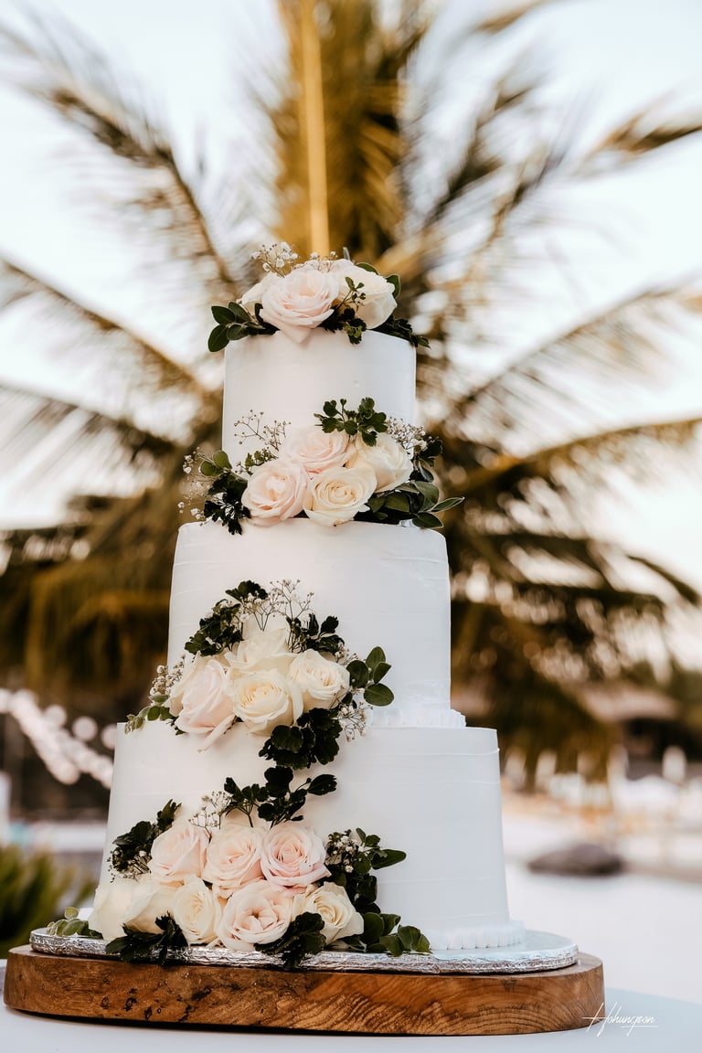 a wedding cake with white flowers on a wooden board