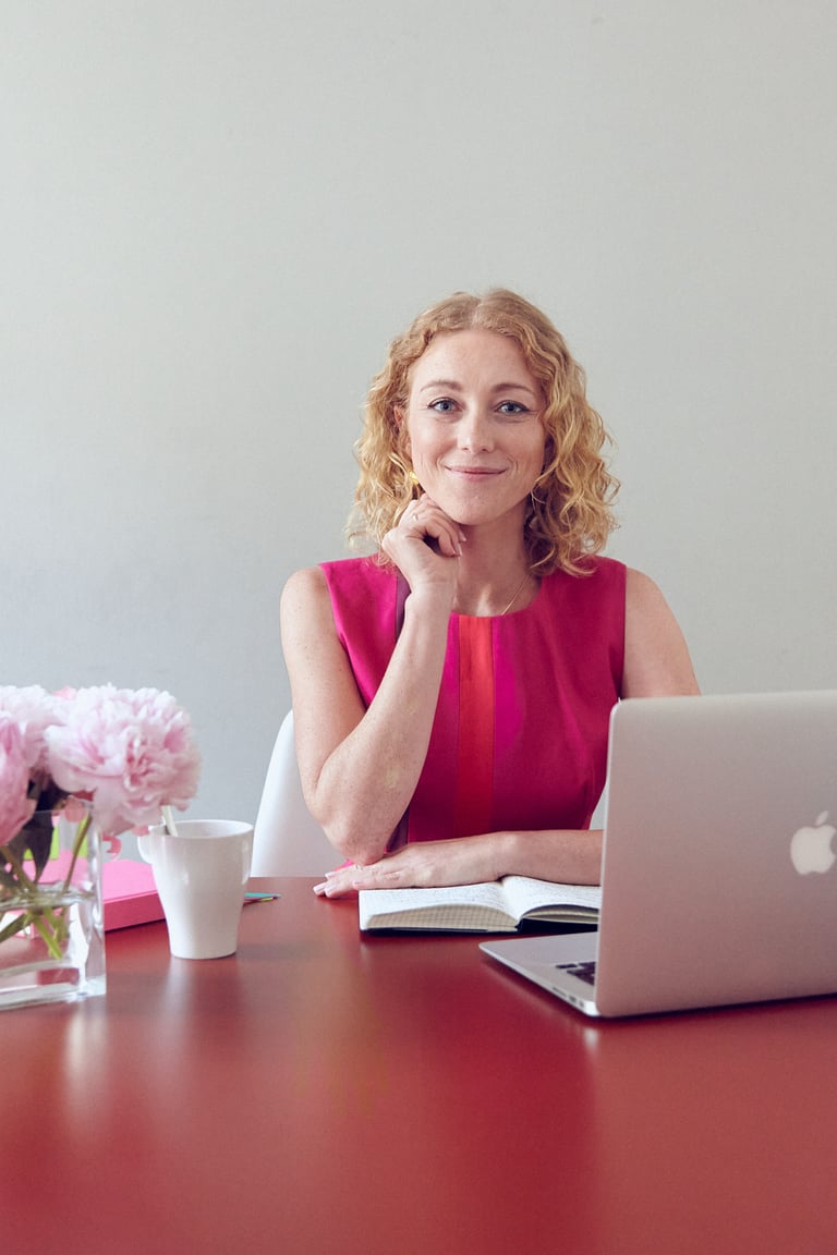 A blonde woman sitting behind a desk.