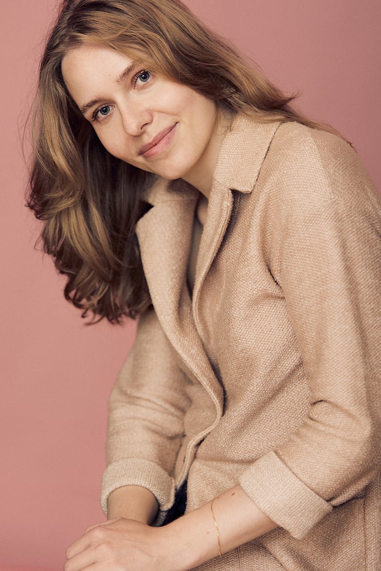 Junge Frau in einem pfirsichfarbenen Mantel.