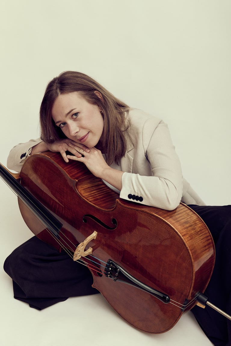 Cellospieler, der in einem Fotostudio auf dem Boden sitzt.