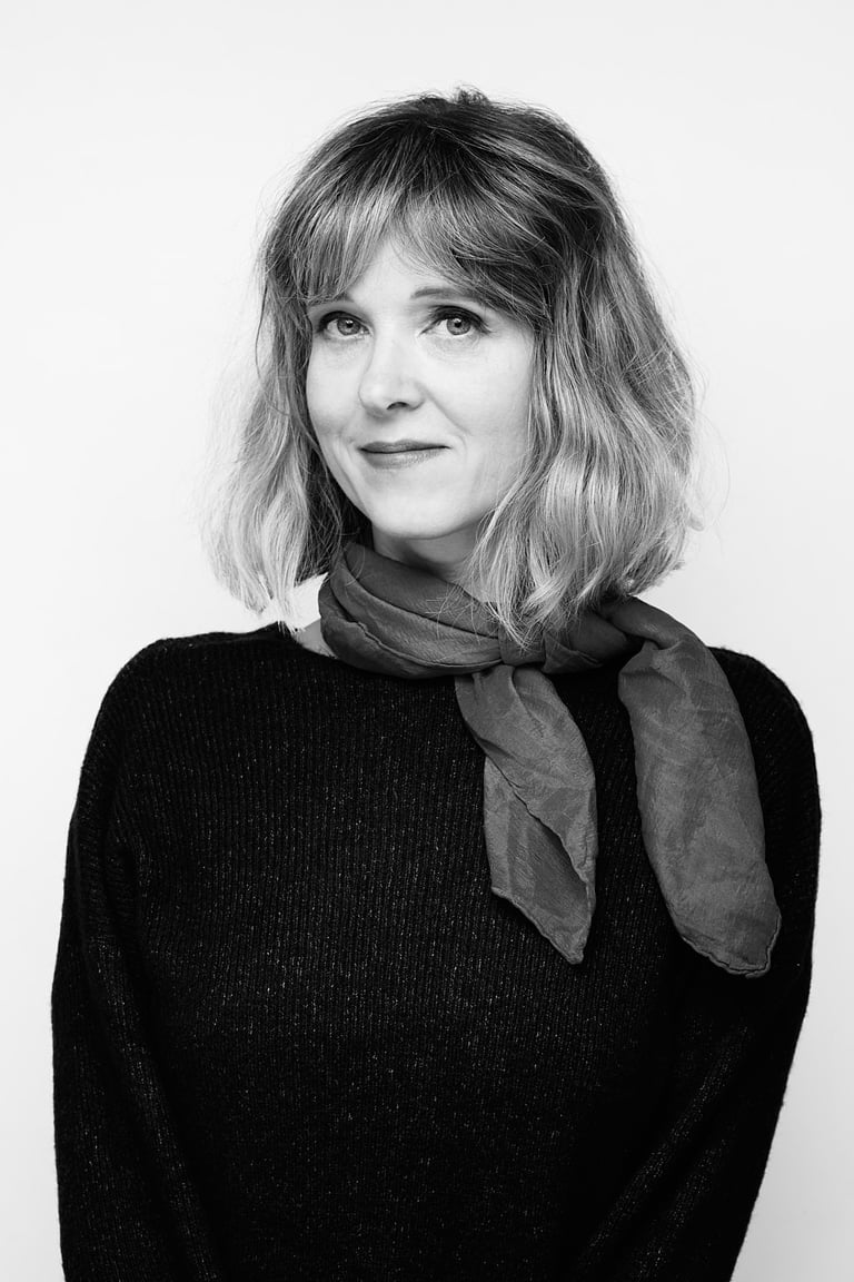 A black and white portrait of a blonde woman wearing a scarf.