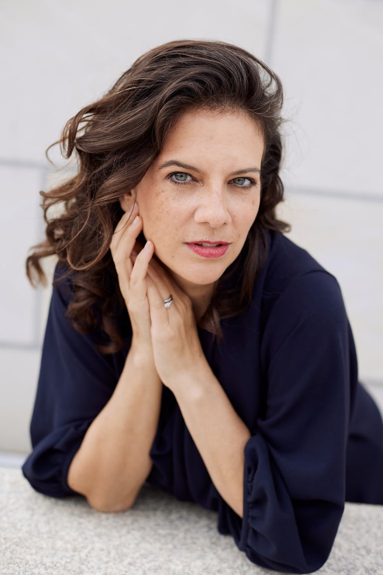 A portrait of a woman in a blue shirt and long brown hair.