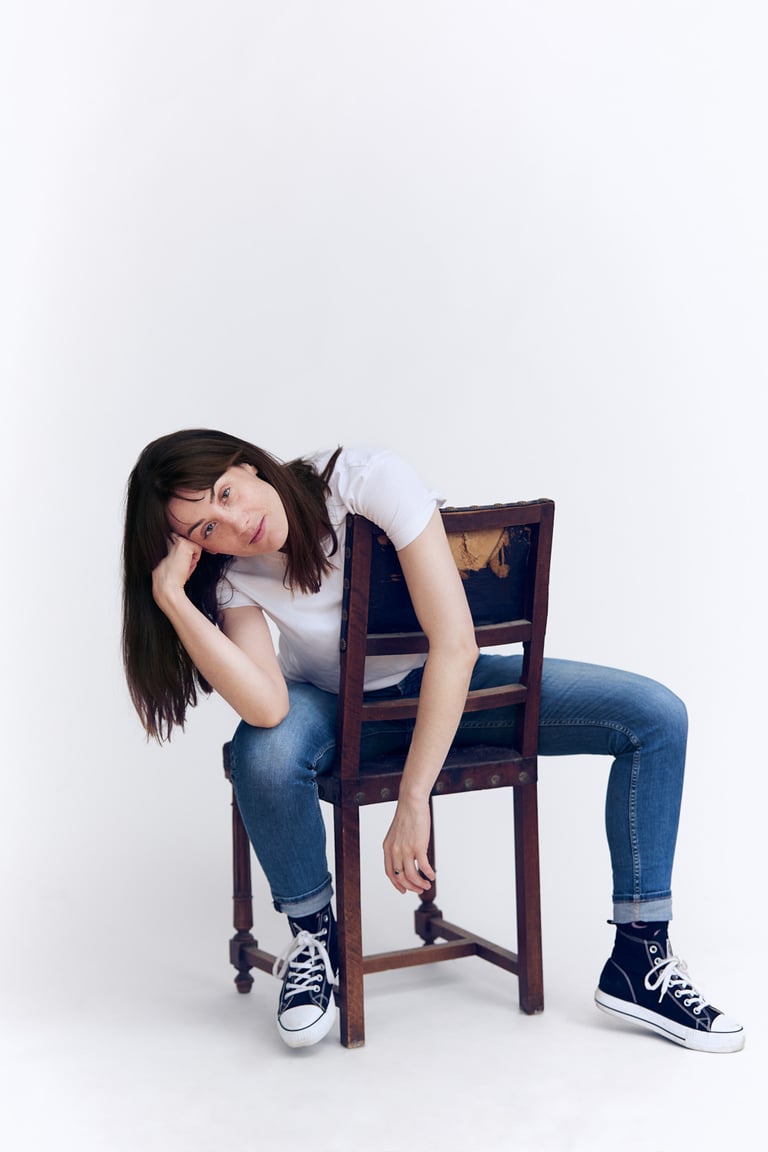 Junge Frau in T-Shirt und Jeans auf einem Stuhl sitzend.