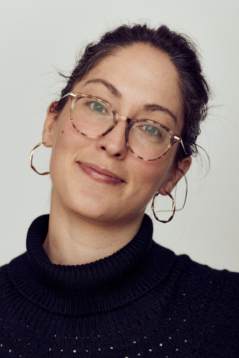 Ein Kopfbild einer jungen Frau mit Brille in einem Fotostudio.
