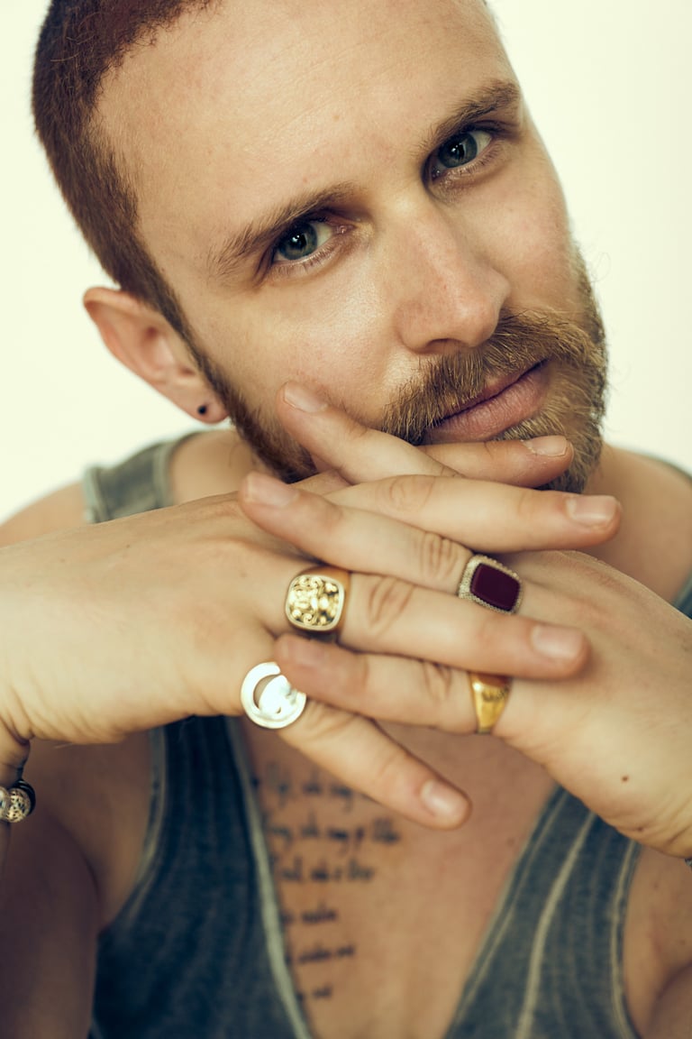 Headshot of an actor wearing rings looking into camera.