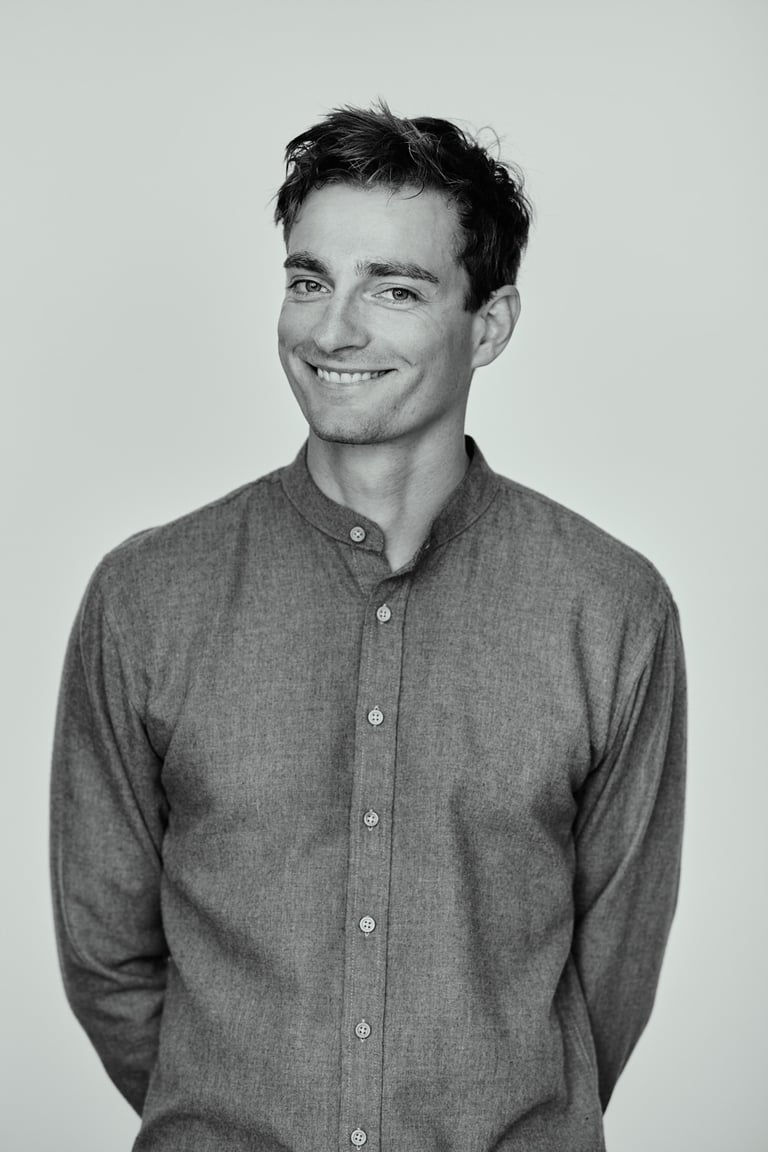 Ein Mann, der in einem Fotostudio lächelt und dessen Hände auf dem Rücken gefesselt sind.