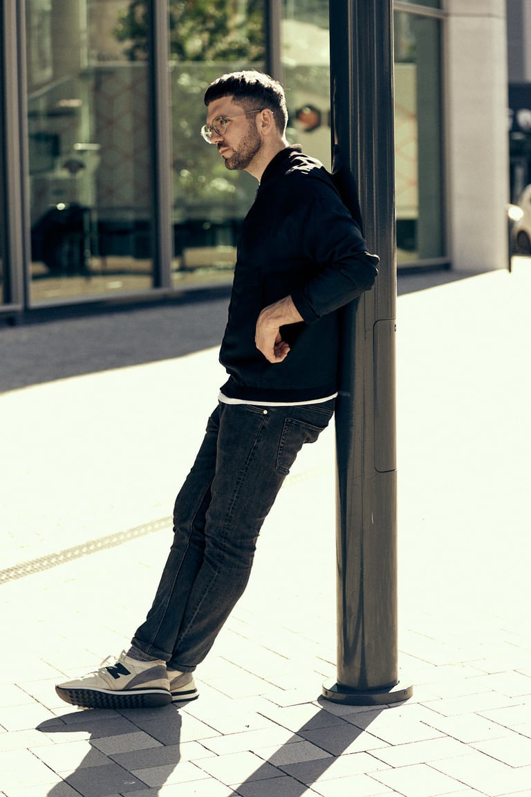 Man photographed leaning on a lamp post.