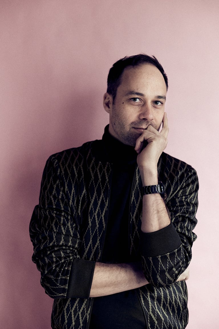 Man photographed in a studio with a pink background.