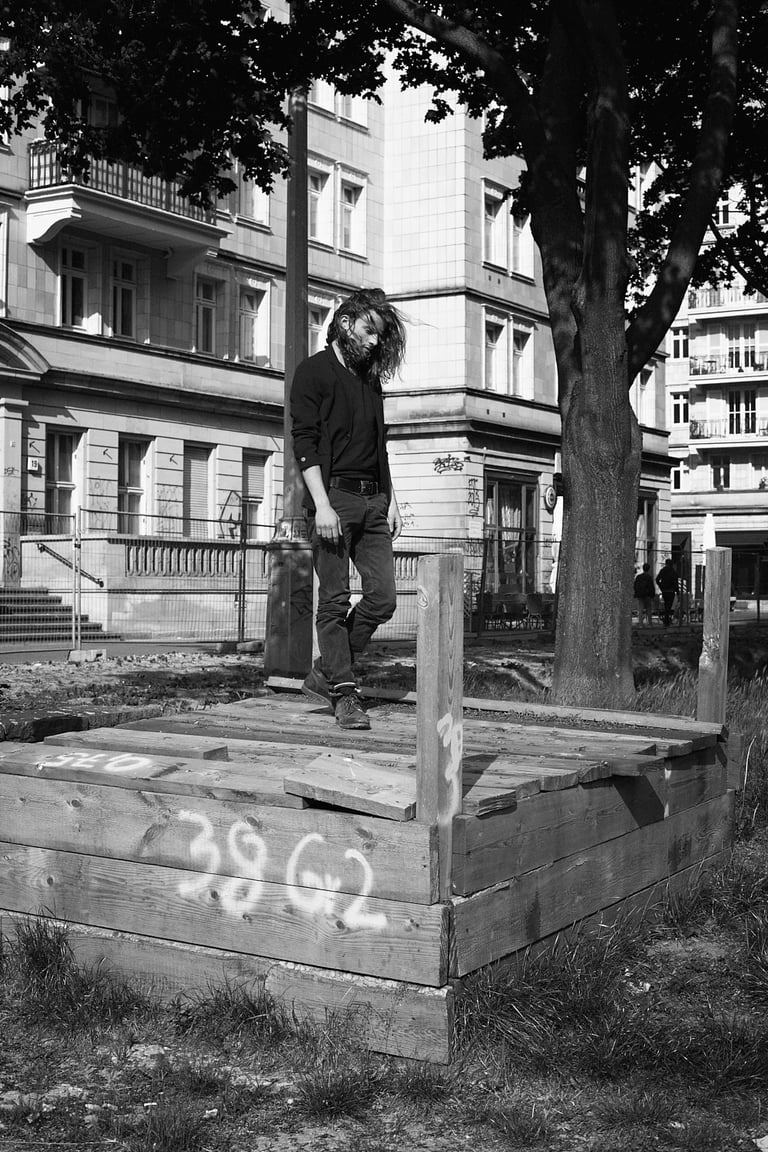 A black and white portrait of a man walking on wooden boards.