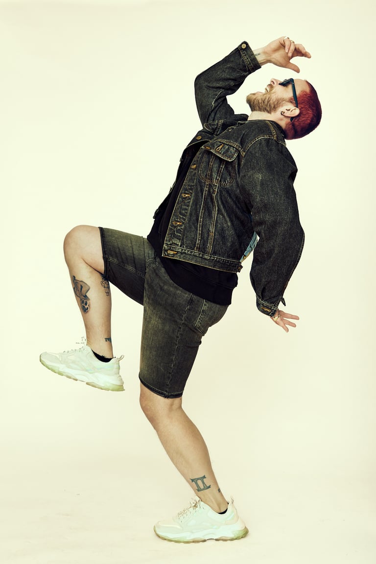 Ein schreiender und springender Mann in Jeansshorts und Jacke.