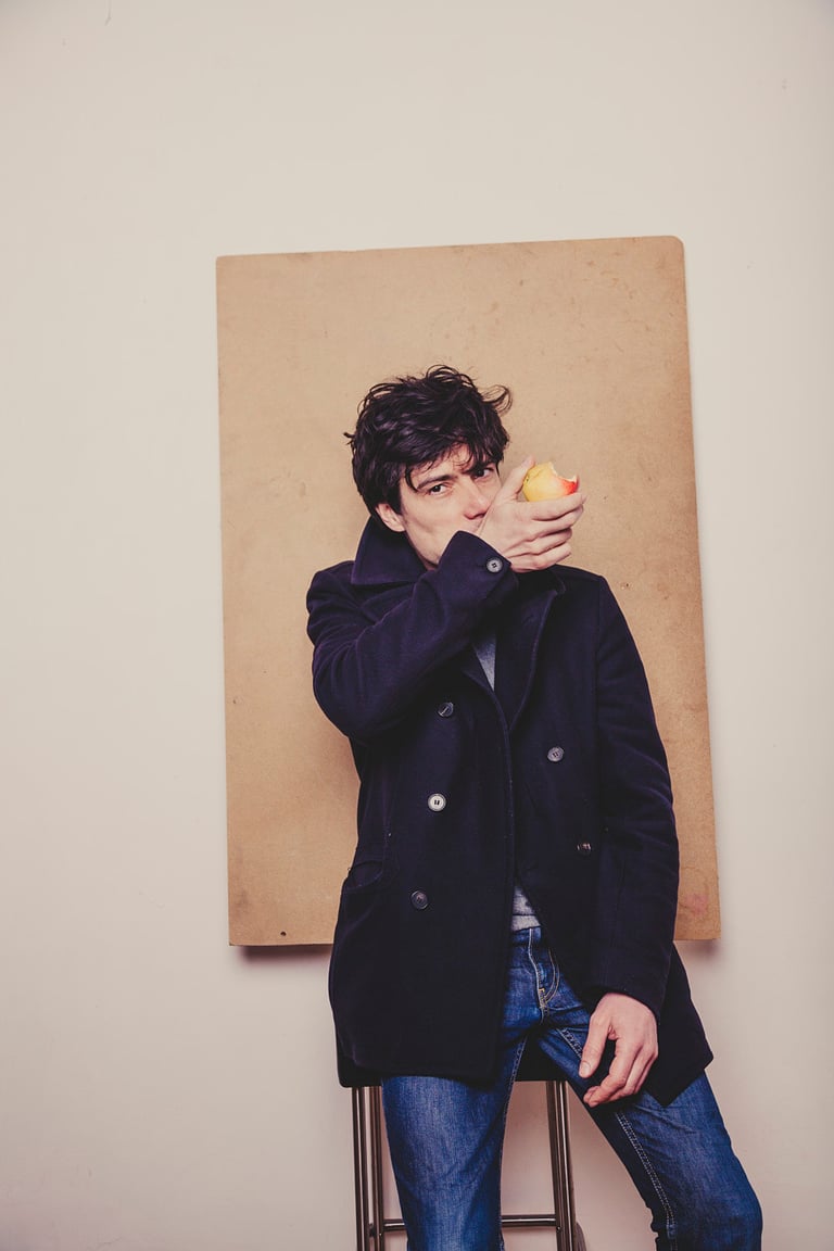 A man eating an apple in a navy coat.