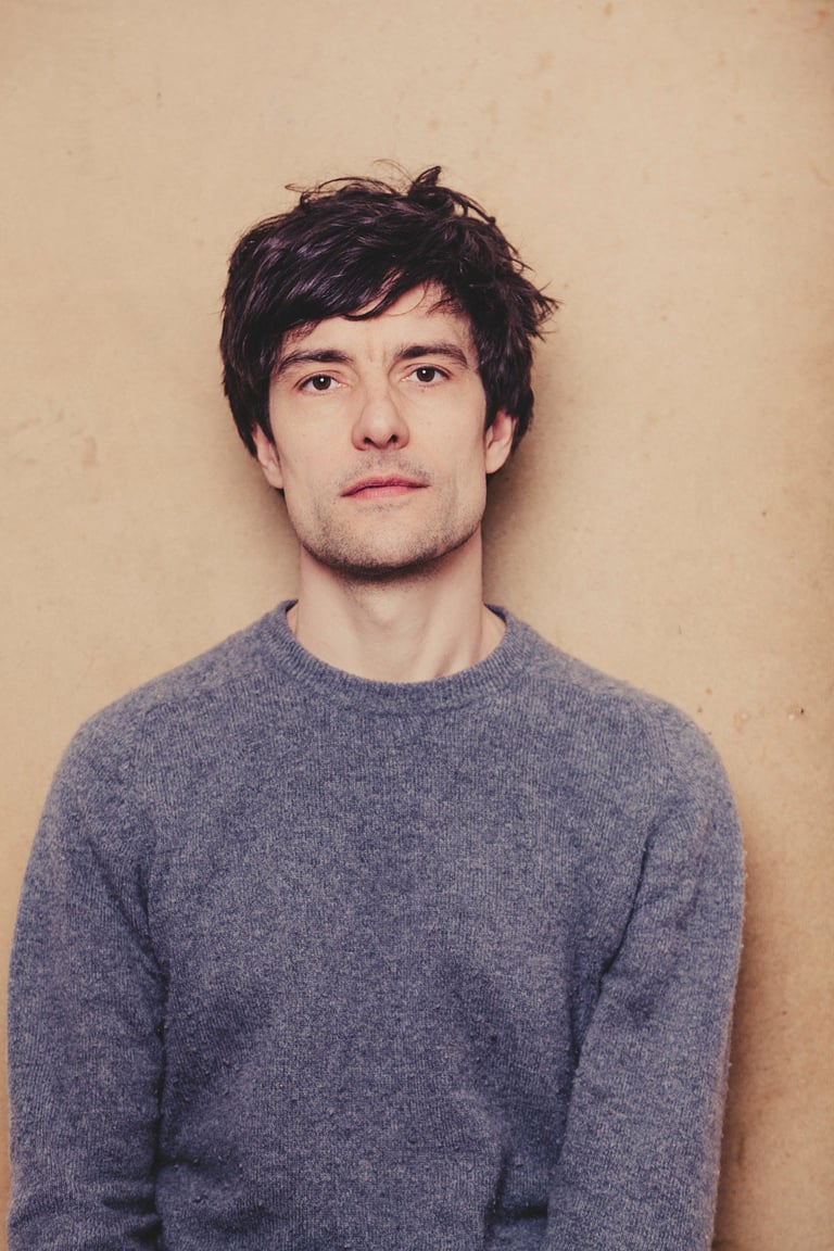 Portrait of musician Noel Rademacher in a grey sweater.
