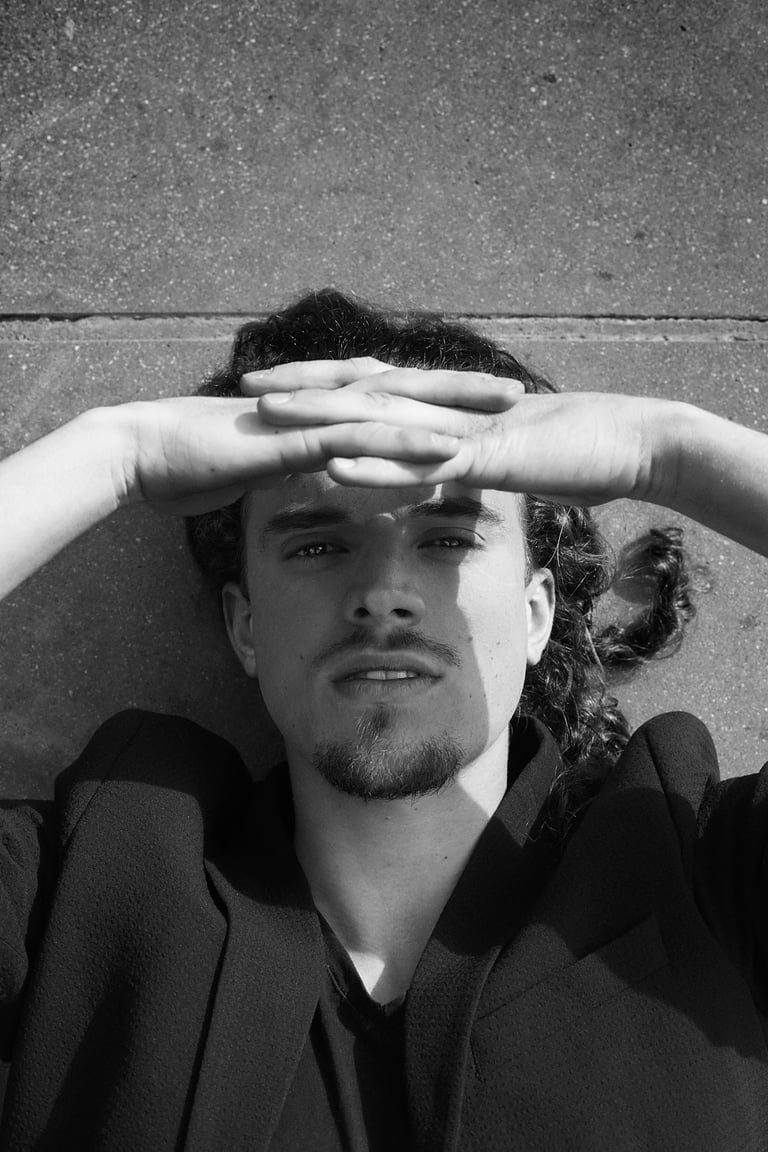 A black and white portrait of an actor lying on concrete.