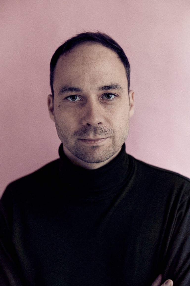 Headshot of a man with a pink background.